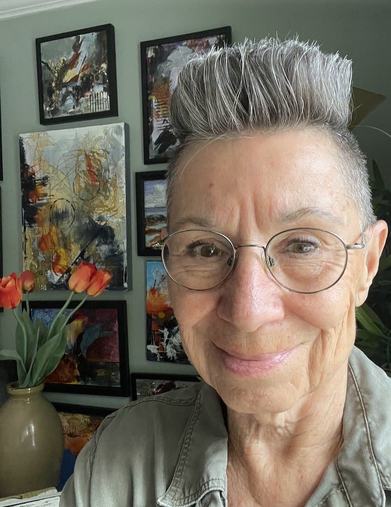 Elizabeth Hlookoff, with her paintings on the wall behind her